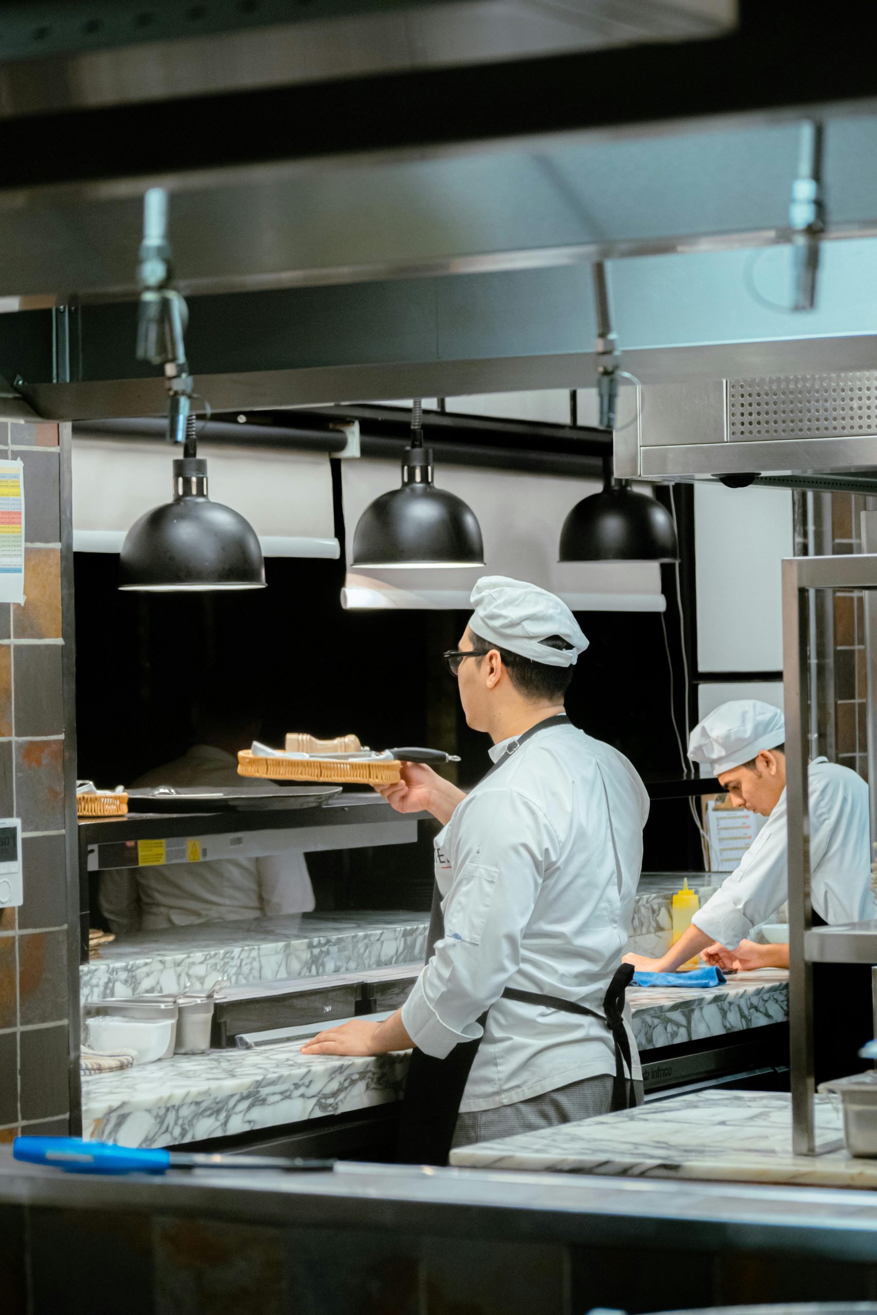 Chefs in a commercial kitchen preparing dishes, with a focus on efficient workspace and quality culinary tools, highlighting the importance of professional kitchen setup.