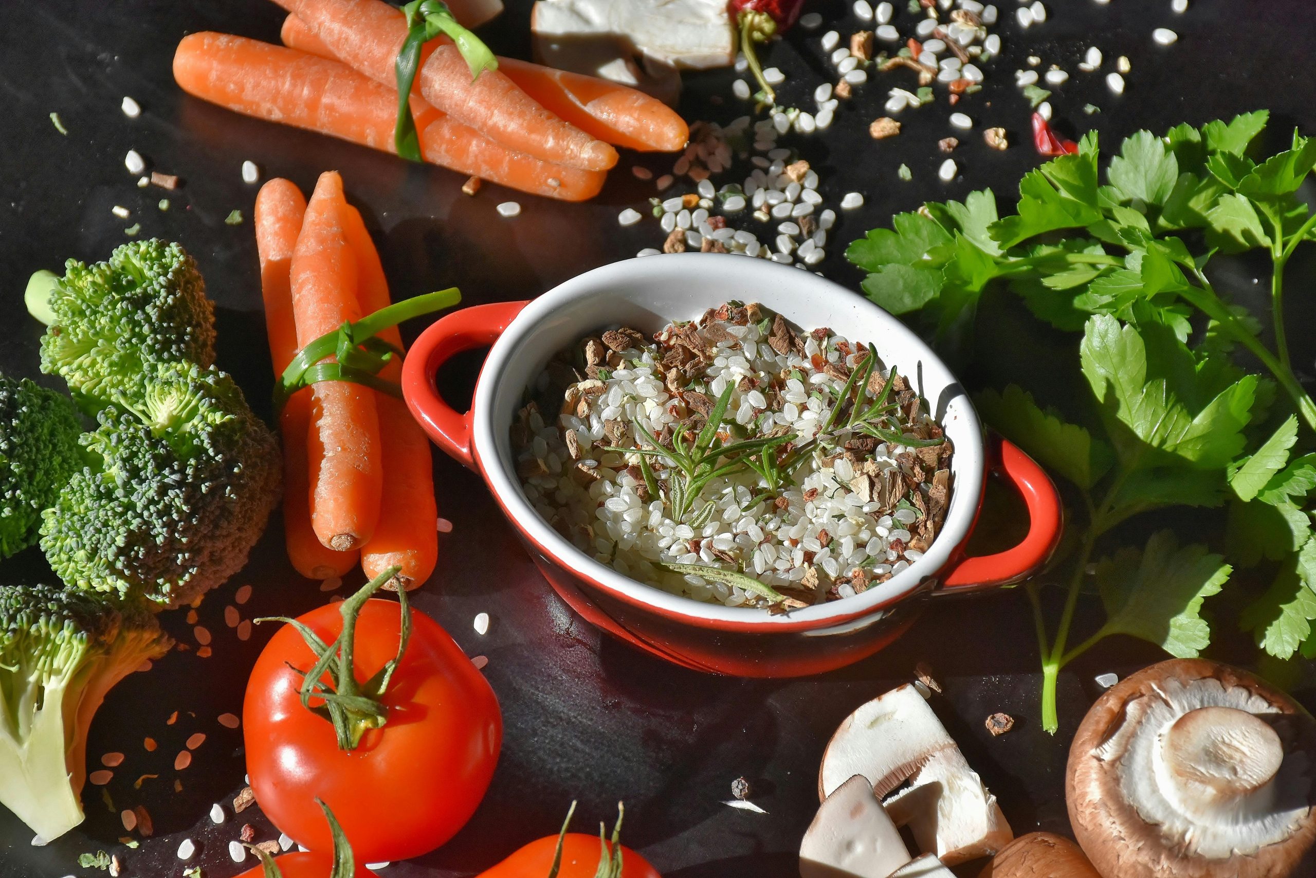 Colorful assortment of fresh vegetables including carrots, broccoli, and tomatoes alongside a small dish of rice and herbs, showcasing culinary ingredients ideal for home cooks and chefs at Standard Restaurant Supply in Denver.